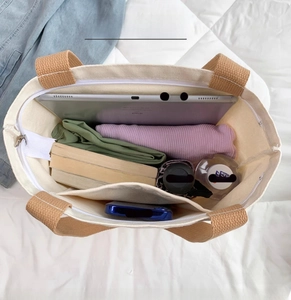 Top view of large capacity canvas tote bag with brown straps showing inner pocket and zipper