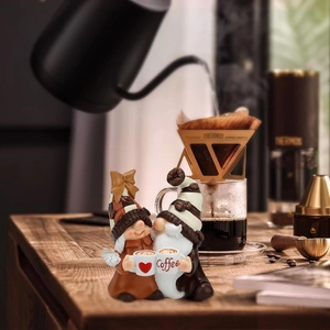 Detail of resin coffee gnome couple ornament on wood table with coffee dripper