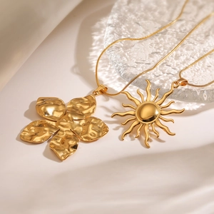Gold plated sunflower and hammer texture floral pendant necklaces on textured glass