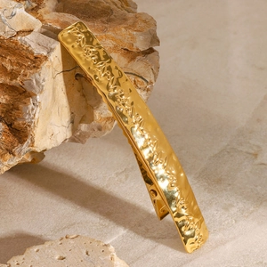 Detail of golden stainless steel hair clip with leaf pattern relief on natural rock