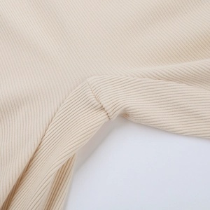 Dettaglio ravvicinato della trama in maglia a coste beige e delle cuciture della tuta