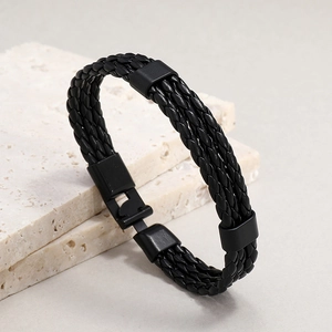 Close-up of black braided leather bracelet with sleek black metal clasp on stone
