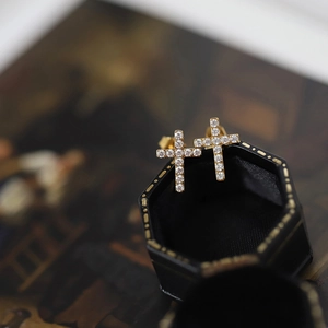 Close-up of gold-plated cross earrings featuring micro-paved white cubic zirconia stones