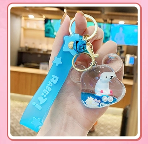 Close-up of cute polar bear liquid quicksand keychain with blue strap and gold hardware