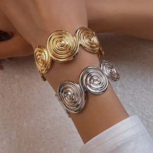 Detail of twisted spiral open cuff bracelets in polished gold and silver metal finishes