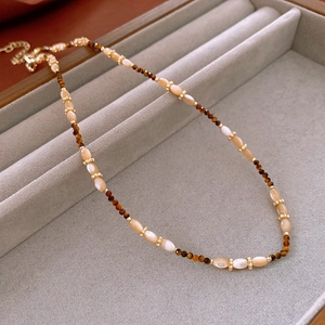 Detail of brown tiger eye beads and cream stones on a floral vintage necklace