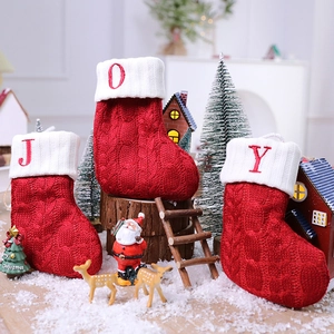 Classic red knitted Christmas stockings with JOY letter embroidery in festive home setting