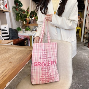 Detail shot of a pink plaid canvas tote bag with GROCERY text and vegetable names