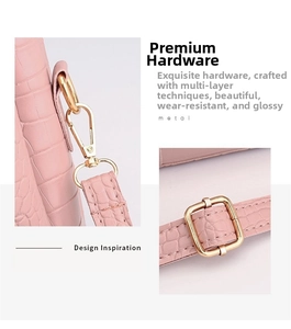 Detail of pink croc-embossed leather handbag showing polished gold hardware and strap hooks