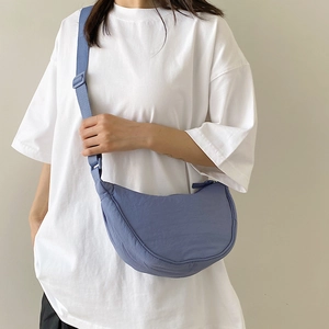 Blue nylon crescent crossbody bag with adjustable shoulder strap worn by a female model