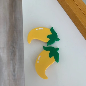 Detailed view of two acetate pepper shaped hair clips in vibrant yellow and green colors