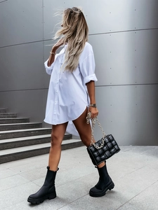 Detail of a white long-sleeve tunic shirt paired with a black woven chain handbag