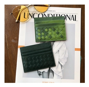 Close-up of woven sheepskin card holders in dark and grass green on a fashion magazine