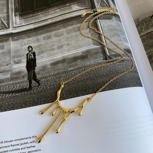 Detail of golden lava pendant necklace on fashion magazine with polished finish texture