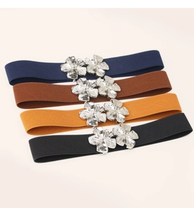 Detail of four elastic waist belts in navy, brown, yellow, and black with silver floral buckles