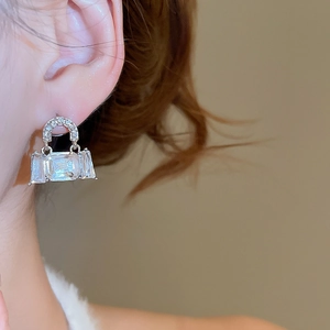 Detail shot of a sparkling handbag-shaped stud earring with cubic zirconia on ear