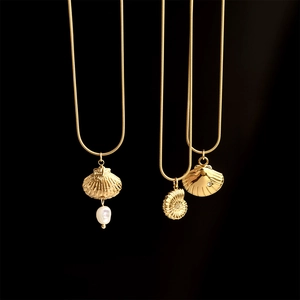 Three gold necklaces with seashell, conch and pearl pendants on black background