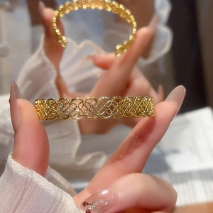 Gros plan d'un bracelet manchette doré avec des motifs ajourés complexes en losange
