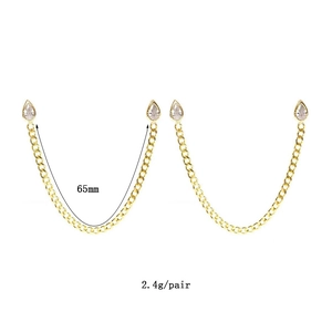 Élégantes boucles d'oreilles chaînes dorées avec zircone goutte sur fond blanc