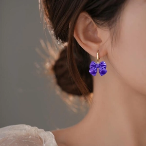 Élégantes boucles d'oreilles nœud violet avec anneaux dorés portées par un mannequin