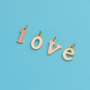 Macro shot of pink and white enamel 'LOVE' letter charms with gold-plated borders
