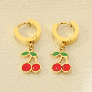 Macro detail of red enamel cherry pendants on gold stainless steel hoop earrings