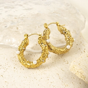 Boucles d'oreilles C dorées texture lave avec perles et strass sur fond de pierre naturelle