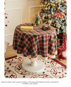 Close-up of red and green plaid round tablecloth with cream fringe tassel decoration