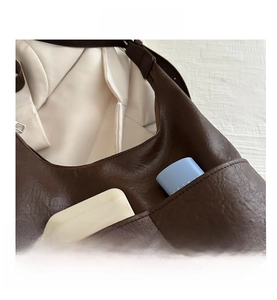 Macro shot of dark brown lychee grain faux leather bag showing spacious front pocket storage