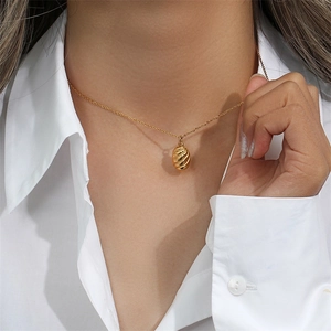 Minimalist gold stainless steel necklace with textured oval pendant worn by a model