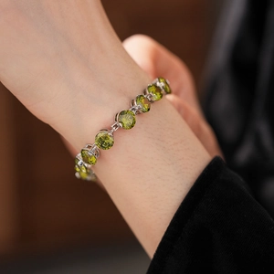 Close-up of olive green zircon tennis bracelet on wrist with elegant silver-tone settings