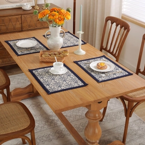Close-up of vintage blue linen placemat with scroll patterns and lace edges on wooden table