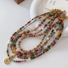 Detail of multi-layered beaded necklace with natural tiger eye, pearls and gold coin pendant