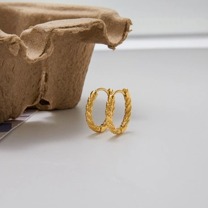 Close-up of gold stainless steel oval earrings with unique woven hammered texture