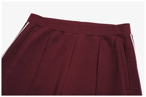 Detail of burgundy sweatpants with elastic waist, side pockets, and white side stripes