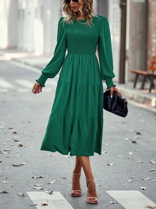 Détail du buste smocké vert et de la jupe à volants sur une robe midi à manches longues