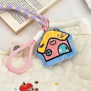 Detail of cartoon house plush charm with embroidery on a white quilted bag