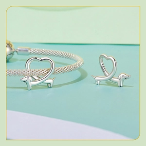 Macro detail of S925 sterling silver dachshund charm with heart cutout on mesh bracelet