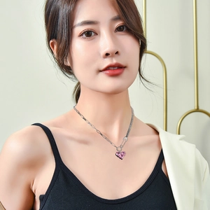 Pink heart crystal necklace with silver paperclip chain worn on neck by a model