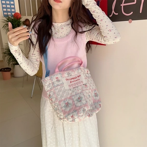 Détail du sac seau matelassé à fleurs avec bandoulière réglable et étiquette