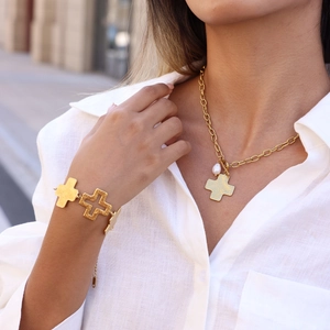 Detalle de collar chapado en oro con colgante de cruz y perla en una modelo