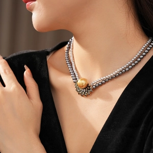 Detail of vintage layered pearl necklace with a gold sunflower pearl pendant