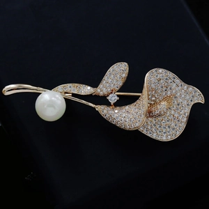 Close-up of golden flower brooch with sparkling crystals and a white elegant pearl