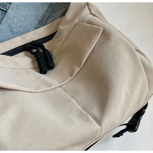 Detail of light khaki tote bag with double black zippers and durable buckle closure