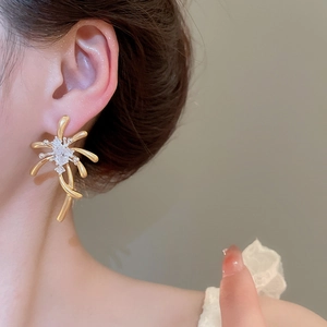 Close-up of golden zircon firework stud earrings worn by a model in a luxury setting
