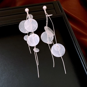 Detailed close-up of long tassel shell earrings with white round discs and pearl studs