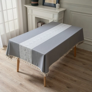 Gray Christmas tablecloth with white reindeer pattern and tassel edges on wooden table