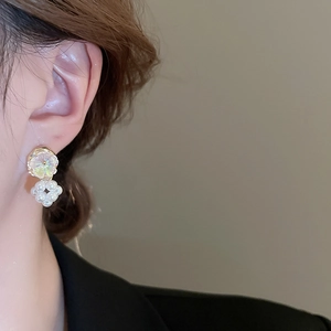 Close-up of elegant flower pearl drop earrings featuring iridescent disks on a model