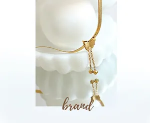 Macro detail of golden butterfly necklace with frosted texture and beaded tassels