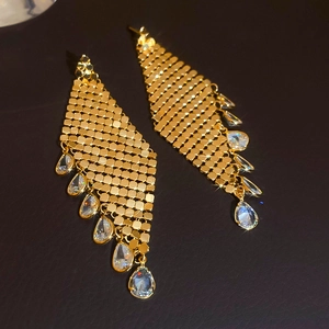 Macro detail of gold-plated mesh earrings with teardrop zircon crystals on leather